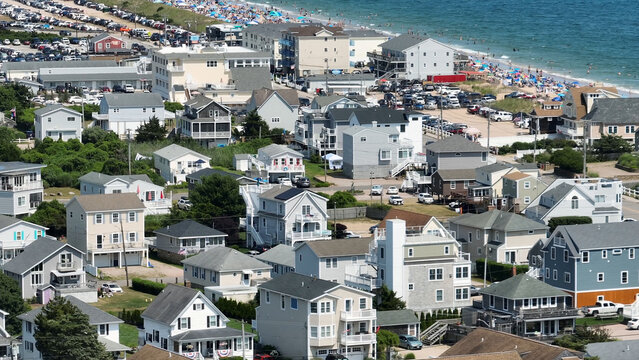 Aerial view of Misquamicut Beach featuring rows of coastal houses, a crowded beach, and parked cars along the shoreline in Westerly, Rhode Island, United States.