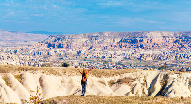 Happy woman hiker standing with arms open on mountain top looking at Goreme valley in Cappadocia Turkey