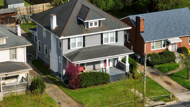 Aerial view of a gray residential house with a front porch, green lawn, and surrounding suburban homes in Lynchburg, Virginia, United States.