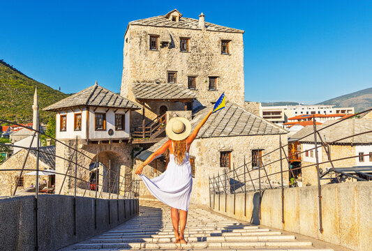 Happy woman dancing on famous historic stari most bridge with Bosnian flag