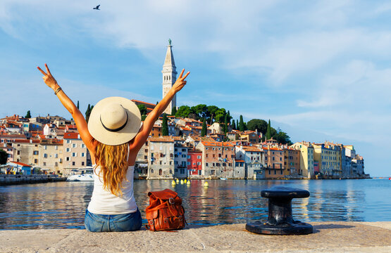 Happy woman sitting by the sea in Rovinj Croatia celebrating summer travel holiday