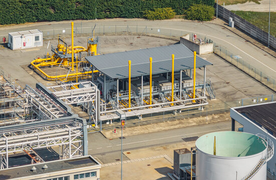 Aerial view of a natural gas pressure regulation and metering station with pipelines, industrial equipment, and storage tanks at a modern power generation facility, Chivasso, Piedmont, Italy.