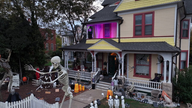Aerial view of a historic house decorated for Halloween with life-sized skeletons, spider webs, and pumpkins on the front lawn in Danville, Virginia, United States.