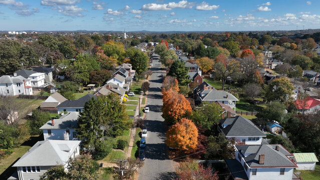 Aerial view of a residential street lined with houses and colorful autumn trees under a clear blue sky in Lynchburg, Virginia, United States.