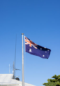 Australian national flag flying on flagpole under clear blue sky