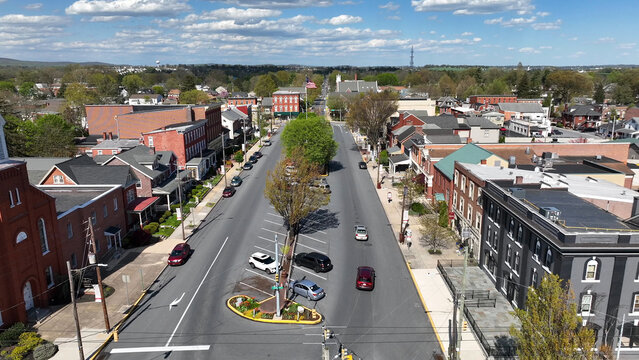 Aerial view of the historic town center of Manheim with brick buildings, tree-lined streets, and cars parked along the road in Manheim, Pennsylvania, United States.