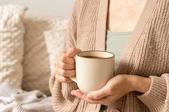 Woman holding warm coffee mug enjoying cozy moment