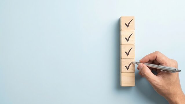 Hand drawing a check mark on a wooden block to complete a task list on blue surface