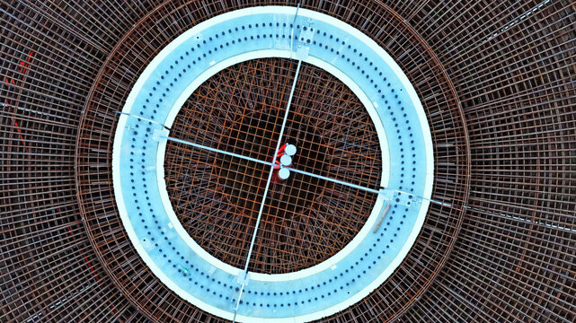 Aerial view of a circular wind turbine foundation featuring intricate steel rebar reinforcement and a central concrete ring in Latvija.