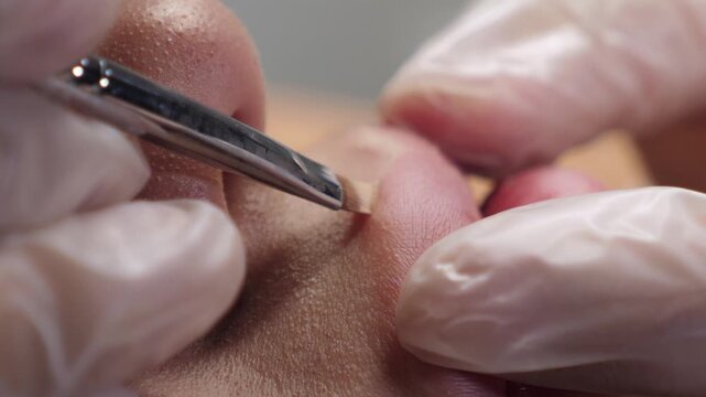 A skilled cosmetologist meticulously applies a lip liner using a brush, preparing for the permanent makeup application.