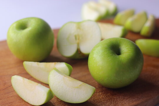 Green apples and fresh apple slices arranged on a wooden board in a styled food setting