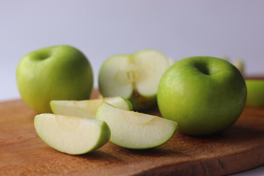 Green apples and fresh apple slices arranged on a wooden board in a styled food setting