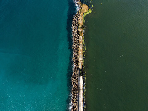 Aerial view of the Rio Ozama breakwater separating the turquoise Caribbean Sea from the darker river waters in Santo Domingo, Santo Domingo, Dominican Republic.
