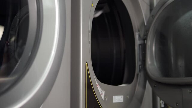 Close-up of a girl opening the door of a washing machine and putting dirty towels inside. The process of washing laundry and clothes in the laundry room is shown.