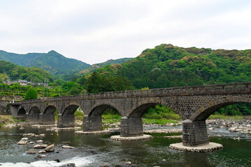Fototapeta premium historic stone arch bridge over river in lush green valley