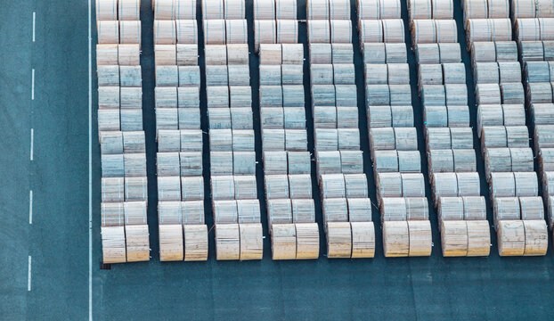 Aerial view of rows of large wooden cable reels arranged in an industrial yard, creating a repetitive pattern linked to logistics and electrical infrastructure in Italy.
