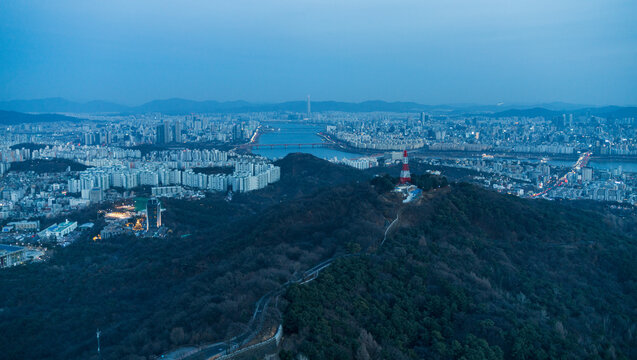 Aerial view of N Seoul Tower atop Namsan Mountain overlooking the Han River and the dense urban skyline of Seoul, South Korea.