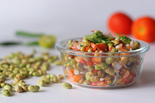 Roasted edamame bean salad with tomato, onion, carrot and fresh coriander in a glass bowl