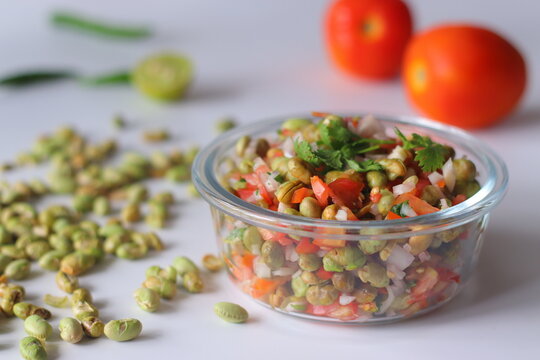 Roasted edamame bean salad with tomato, onion, carrot and fresh coriander in a glass bowl