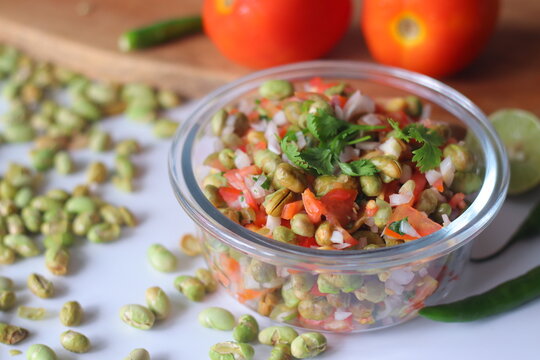 Roasted edamame bean salad with tomato, onion, carrot, coriander and lime served in a glass bowl