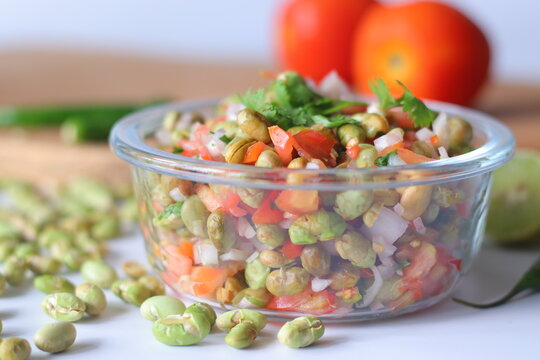 Roasted edamame bean salad with tomato, onion, carrot, coriander and lime served in a glass bowl
