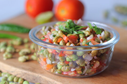 Roasted edamame bean salad with tomato, onion, carrot and fresh coriander in a glass bowl