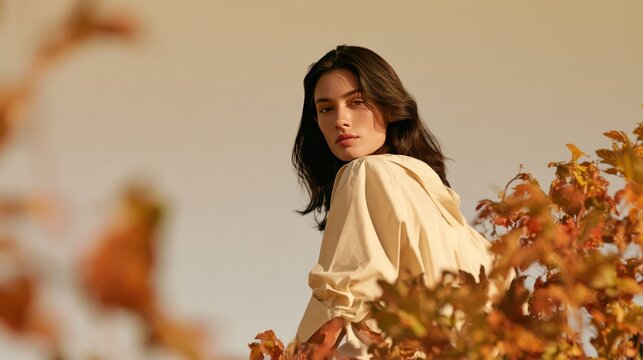 Autumnal Muse: A beautiful young woman with flowing dark hair poses gently amidst the warm hues of autumn foliage, her gaze soft and contemplative.