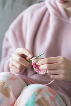 Person knitting with yarn while sitting indoors