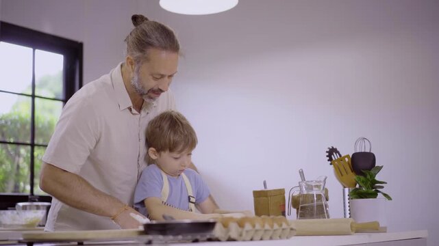 Caucasian family with parents teaching son kneading dough in kitchen