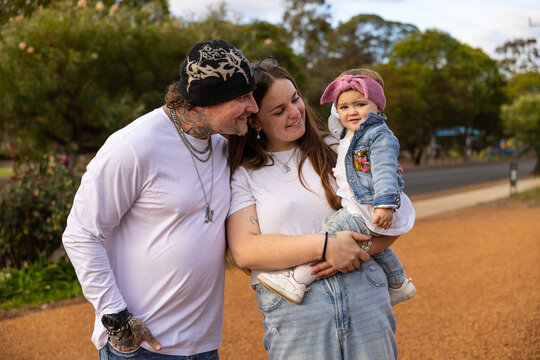 Happy couple standing outdoors while holding their baby girl