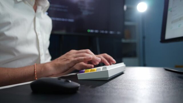 Coder focuses intently on compact keyboard at night desk