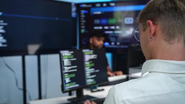 Coder types code under glowing blue screen light