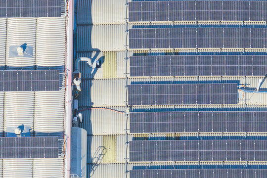Aerial view of solar panels installed on a large industrial roof with metal corrugated sheets and ventilation systems in Arezzo, Tuscany, Italy.