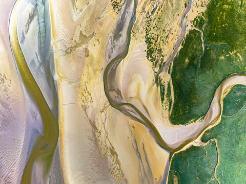 Aerial view of the intricate tidal channels and sandbanks of the Baie de Somme with vibrant green salt marshes and winding waterways in Saint-Valery-sur-Somme, Hauts-de-France, France.