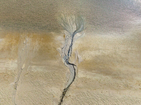 Aerial view of the intricate tidal channels and sand patterns of the Baie de Somme at low tide, showcasing natural textures in Saint-Valery-sur-Somme, Hauts-de-France, France.