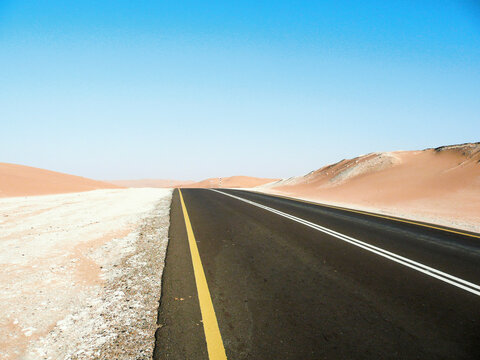 An empty highway disappears into a desert landscape
