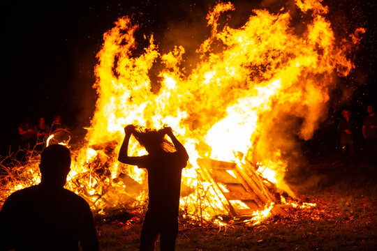 Silhouetted people celebrating around a large bonfire at night