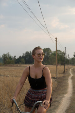 Stylish woman with a buzz cut riding a bicycle on a rural path