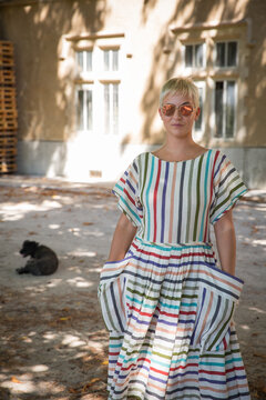 Chic woman with short hair in a colorful striped dress outdoors
