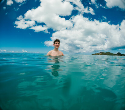 Young man smiling while swimming in tropical ocean water