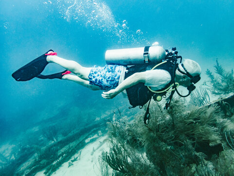Man scuba diving horizontally above a coral reef