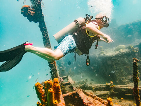Senior man scuba diving and exploring a sunken shipwreck