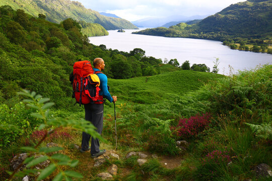 Man hiking with backpack looking at beautiful lake view in Scotland