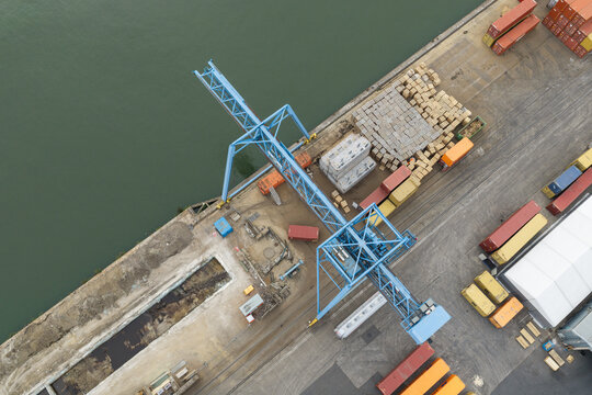 Aerial view of Haven Genk container terminal with a large blue port crane, shipping containers, and industrial infrastructure along the waterfront in Genk, Vlaanderen, Belgium.