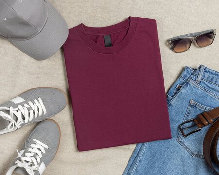 Blank dark red folded t-shirt mockup, crewneck flat lay with denim jeans and mens accessories