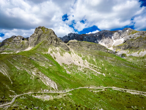Aerial view of Bobotov Kuk with lush green mountain slopes, rocky peaks, and a winding road through the landscape in Zabljak Municipality, Montenegro.