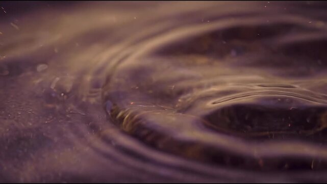 Luxury home fragrance oil appears as a translucent muted bronze-violet liquid surface with slow abstract material background