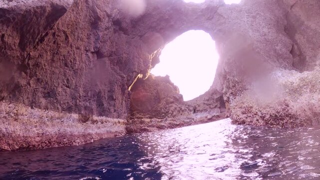 swimming on the ocean sea water surface at the passage way leading to Lover's cave inside with huge reef rock at both sides during good weather clear day with blue sky and sea in Orchard Island in Tai