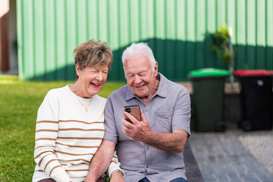 mobile phone device held in hand of senior couple as they smile at photos of grandchildren