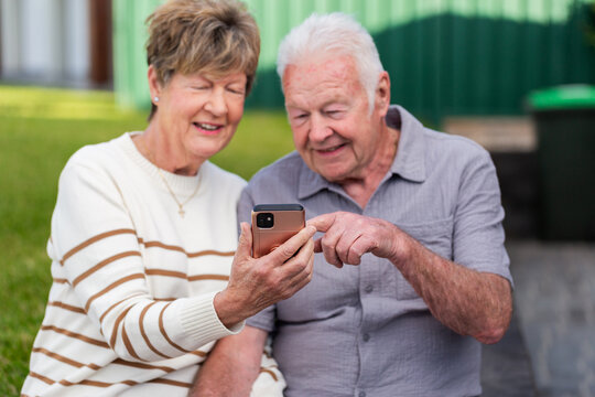 mobile phone device held in hand of senior couple as they smile at photos of grandchildren